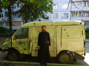 Отець Михайло Станчишин біля авта, яке врятувало його життя, бо стояло якраз перед вікном квартири, коли розірвалася касетна бомба. Харків, 11 квітня 2022 р., 18:23